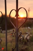 Ornate wrought iron scroll work outside at sunset.