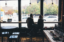 couple sitting together in a restaurant in front of a window 