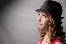 A girl in a hat looking up.