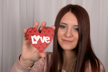 girl holding up a heart with the word love 