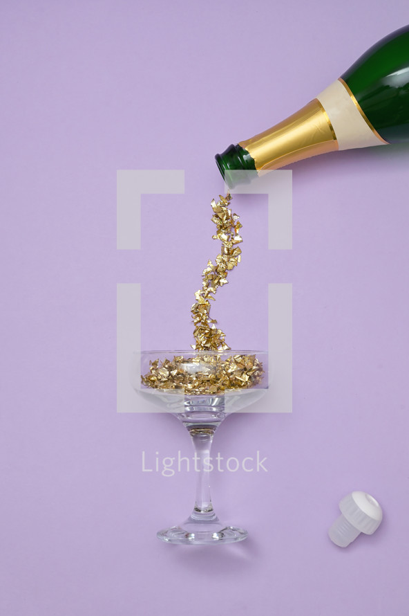 Champagne bottle with gold confetti pouring into glass