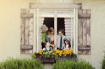 Family in a window with flower boxes.