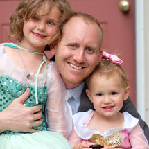 a father hugging his daughters dressed as princesses 