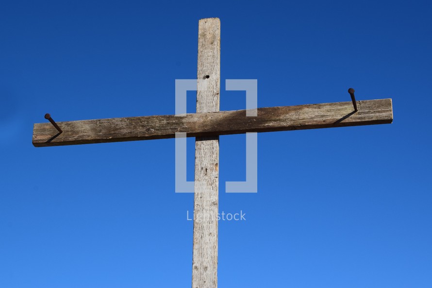 cross with nails against a blue sky 