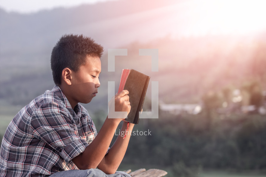 a boy child reading a Bible 