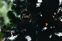 noel ornament hanging on a Christmas tree 