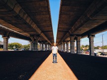 A man standing under an overpass.