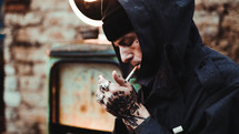 man with tattooed hands smoking a cigarette 