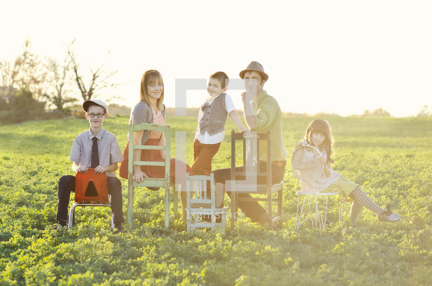 Family sitting on chairs in a meadow.