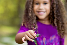 a young girl holding a small purple flower 
