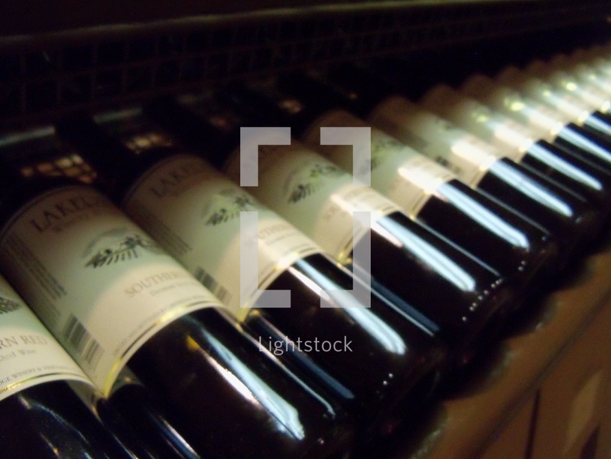 A row of Wine Bottles in a basement winery with labels in a wine rack. 
