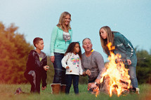 a family sitting by a campfire roasting marshmallows 