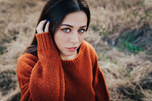 a woman posing in an orange sweater 