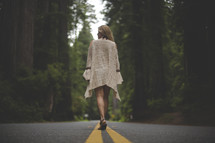a woman walking on the center lines of a road 