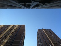 looking up at the blue sky between skyscrapers