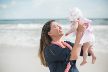 mother holding her newborn daughter on a beach 