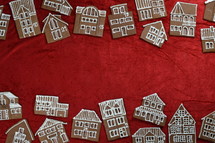 two rows of  self baked different gingerbread house cookies with numbers on them as advent calendar on red