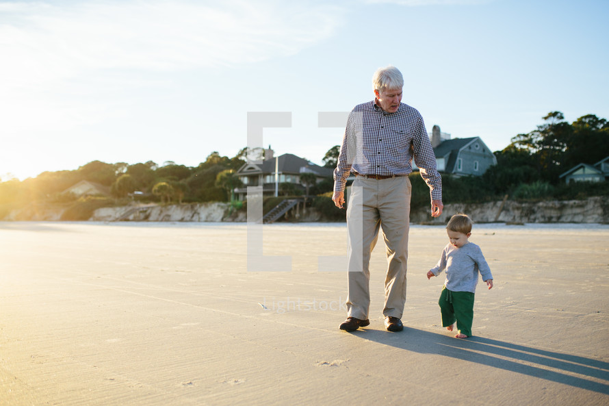 grandfather and grandson walking on a beach 