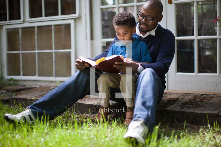 Father and son sitting together and reading the Bible.
