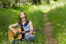 woman in a field playing her guitar 