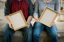 man and woman holding empty frames 