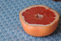 Half of a grapefruit on a blue tablecloth.