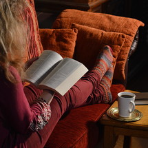 woman reading her bible comfortably on a sofa at home 
