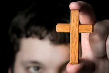 man holding up a small wood cross 