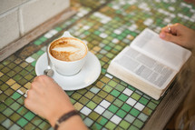 woman reading a Bible and a cup a cappuccino 