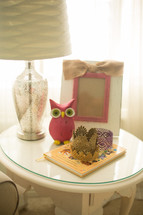 frame, owl figurine, book, and lamp on an end table 