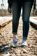 feet of a teen girl standing on a railroad track 