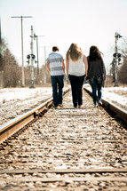 teens walking on a railroad track 