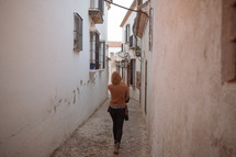 a woman walking through a narrow alley 