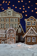 home made delicious sweet traditional gingerbread town with bokeh sky out of blue velvet and christmas lights as advent decoration
