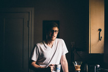 A man standing in a kitchen having a cup of coffee.