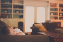 a toddler boy napping on a couch 