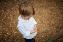 a toddler holding his hands and looking down 