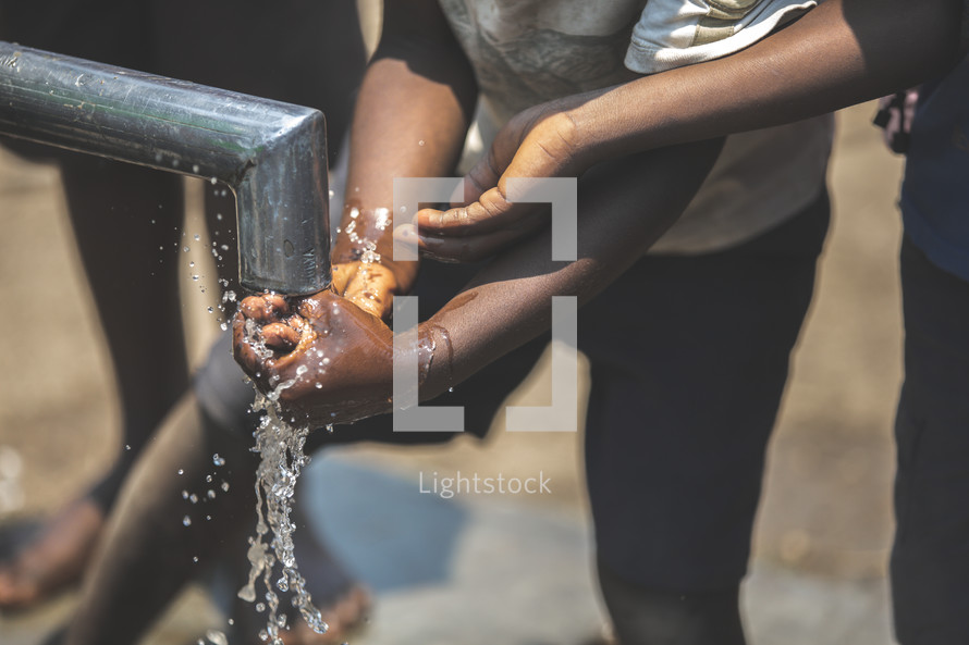 children washing hands in running water 