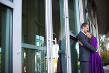 Man and woman hugging in front of a building.