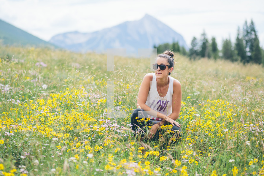 woman squatting in a field of wildflowers 