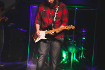 a man playing an electric guitar on stage 