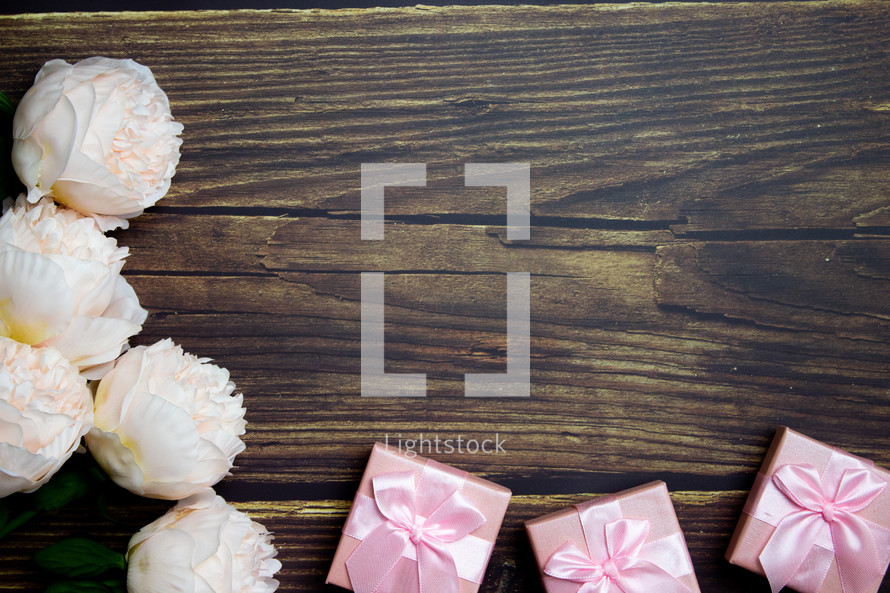 Pink flowers and gifts on wooden table