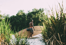 a man with a paddle board walking in shallow water 