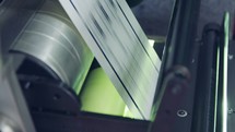 Closeup on paper moving through a large industrial printing machine