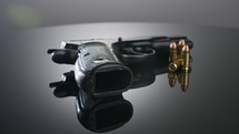 Gun Control. Studio shot of a 9mm gun rotating on a reflective surface
