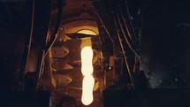 Slow motion of Molten glass pouring out of a Glass melting furnace in a bottle production facility.