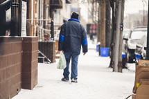 a man walking on a sidewalk in snow 