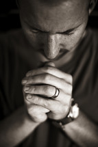 A married man prays with head bowed and eyes closed