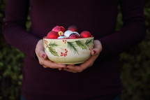 a woman holding a bowl of ornaments 