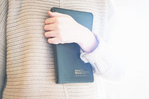 a woman holding a Bible against her chest 